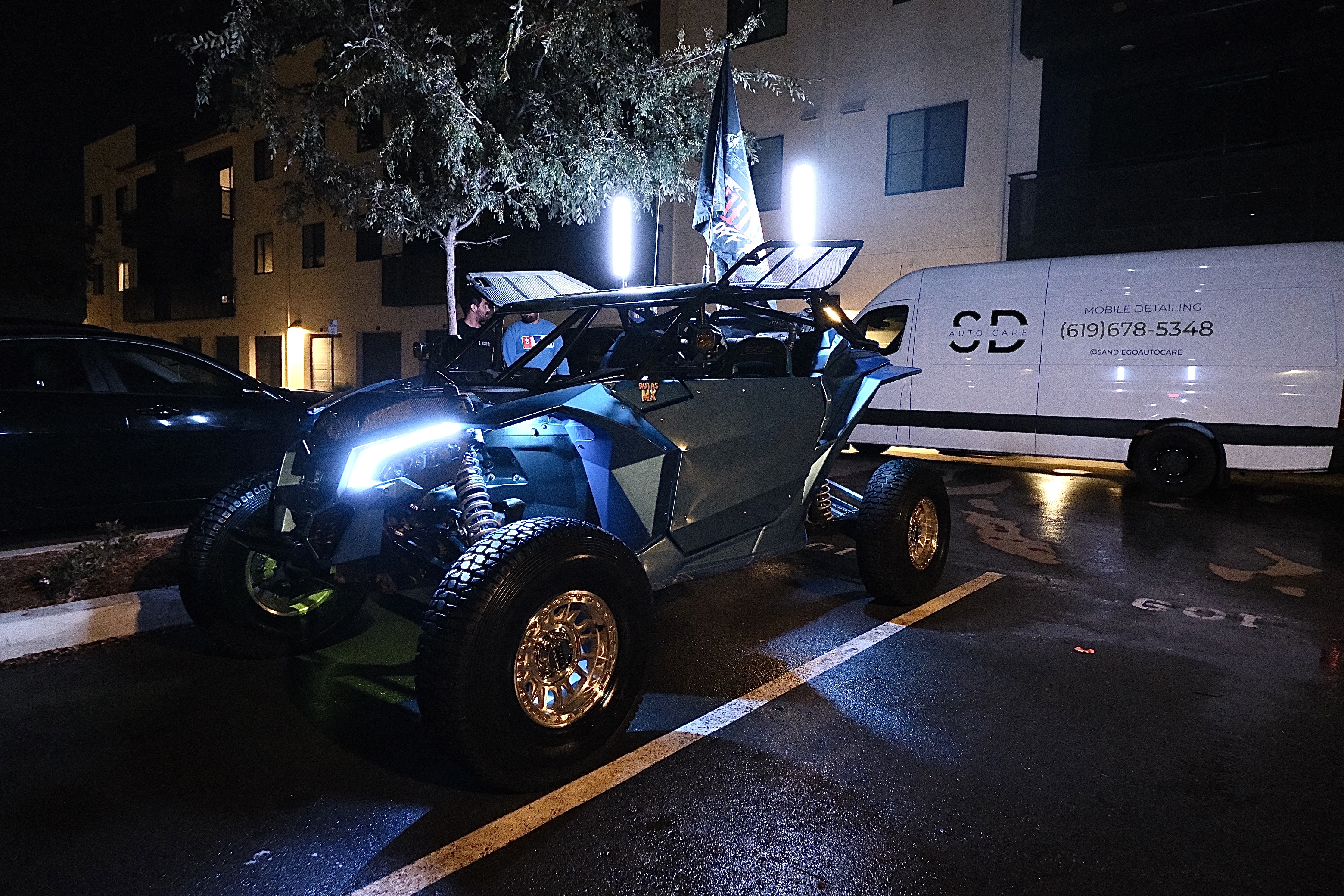 Can-Am X3 side-by-side lit at night next to the San Diego Auto Care service van